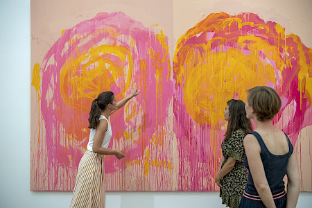 Three people stand in front of painting with abstract flowers in pink and orange