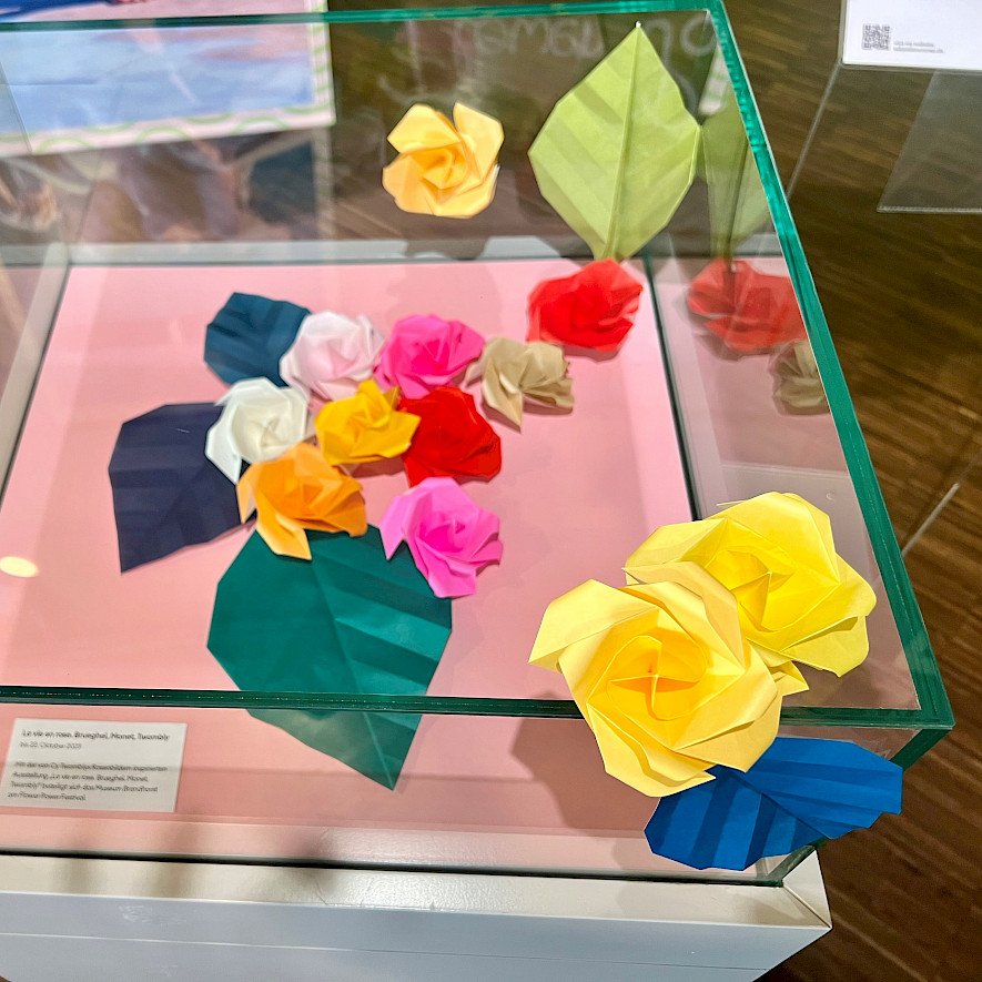 folded paper flowers and paper leaves in and on a desk display case